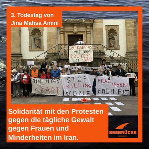 3. Todestag von Jina Mahsa Amini,  Solidarität mit den Protesten gegen die tägliche Gewalt gegen Frauen und Minderheiten im Iran. Auf dem Foto steht die Menschen der Mahnwache mit Transparenten vor der Franziskaner Kirche - auf dem Boden sind Plakate mit den Namen der Ermordeten zu sehen.