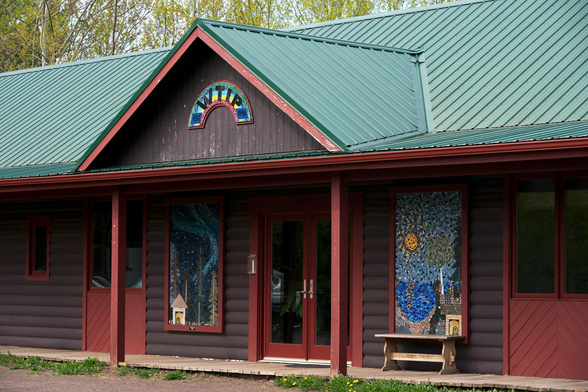From the article, the log-cabin feel of the WTIP studios in Grand Marais, Minnesota. Green metal roof; reddish-brown walls; artwork flanking the glass-door entrance.

WTIP North Shore Radio is seen along Hwy. 61 in Grand Marais, Minn. (Erica Dischino/For the Minnesota Star Tribune)