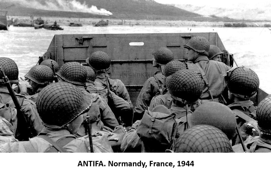 Photograph of U.S. soldiers on a landing craft approaching a beach on D-Day during World War 2.