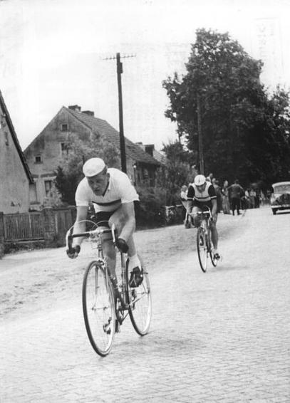 Historic photograph of two cyclists in a road race, Täve Schur overtaking a competitor, GDR championship 1955. Bundesarchiv, Bild 183-31636-0003 / CC-BY-SA 3.0, CC BY-SA 3.0 DE <https://creativecommons.org/licenses/by-sa/3.0/de/deed.en>, via Wikimedia Commons