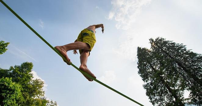 Un homme marche en équilibre sur une corde, symbolisant la psychothérapie entre efficacité et incertitudes.