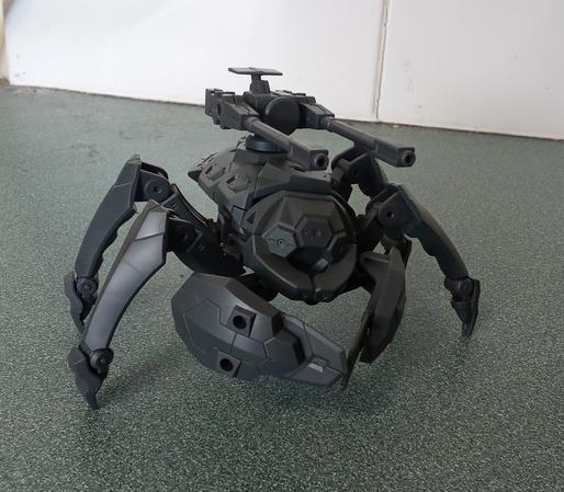 A grey mecha model. A bug robot with claws and twin cannons on its back.