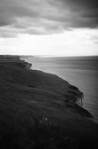 A black and white photography of a cliff and the sea