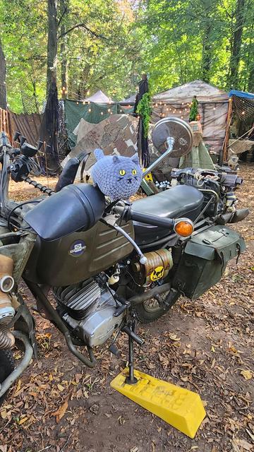 A gray round plush cat on a motorcycle