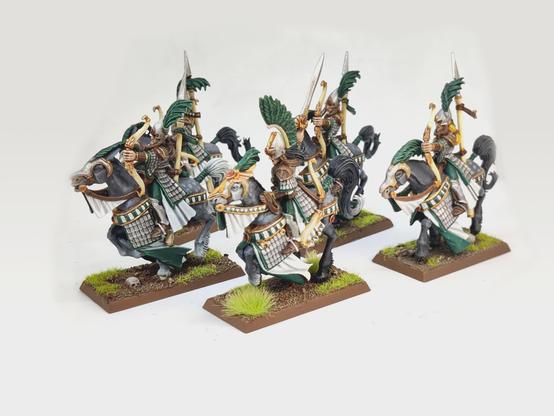 A unit of five Ellyrian Reavers from Warhammer Fantasy Battle/The Old World. They are painted in a mixture of green and white, carrying bows and spears and riding grey horses.