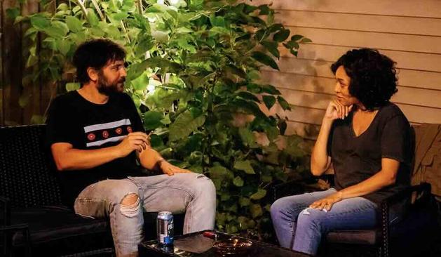 Josh Radnor and Chandra Russell sit in a garden smoking, drinking beer, and talking