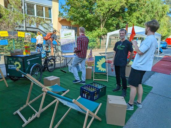 Grüne Liegestühle, drei Menschen, eine Pinnwand mit Stadtplan.