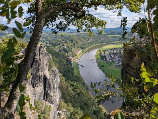 links ein Sandsteinfelsen und Baum unten im Tal ein Fluss auf dem ein Boot Fahrt