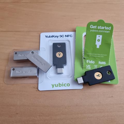 Three intenso usb thumb drives, and two YoubiKeys 5C NFC, on a table. One yubikey is still in it's package, the other one opened up. As are the three thumb drives.