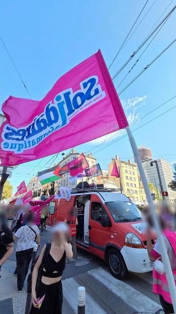 Photo du cortège de la manifestation ce vendredi 19 septembre à Lyon, suite à l'appel à la grève reconductible par Solidaires Rhône. En premier plan, on y voit un drapeau Solidaires Informatique qui flotte au vent, puis le camion Solidaires orné des drapeaux de tous les syndicats de Solidaires Rhône et d'un drapeau de la Palestine, avec des manifestant·es tout autour.