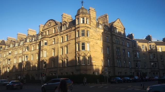 Handsome Victorian stone tenements, lower levels already in evening shadows, upper levels glowing in the sunset light