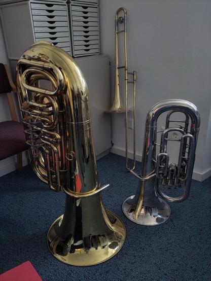 Eine Tuba, ein Euphonium und eine Posaune auf einem blauen Teppich