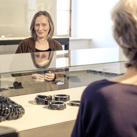 Andrea Auer bei der Finissage ihrer Ausstellung mother of pearls im Schlossmuseum Linz.

In der Vitrine sind Armreifen und Geschmeide aus Bakelit ausgestellt, dem ersten industriell verwendeten Kunststoff.

Viele Häuslbauer kennen den elektrotechnischen Fachbegriff des „Bakelit-Lusters“ – eine schöne Umschreibung für die Rohinstallation aus E27-Fassung und Glühbirne, die als Provisorium nach dem Einzug ins neue Haus „ewig“ Licht gab.