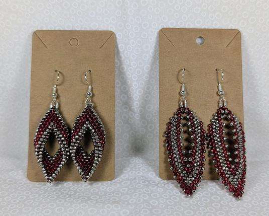 Two pairs of silver and red beaded earrings displayed side by side. One set is twisted peyote while the other is Russian leaves.
