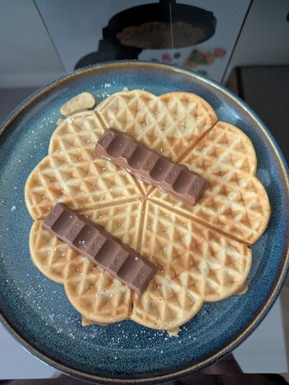 Frische heiße Herzwaffel mit zwei schmelzenden Riegeln Kinderschokolade