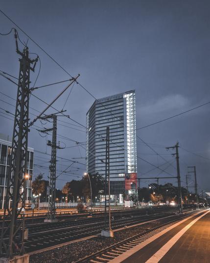 der hinter dem Hauptbahnhof Mannheim sich befindliche, spiegelnde Viktoriaturm zur blauen Stunde, im Vordergrund das Gleisbett.