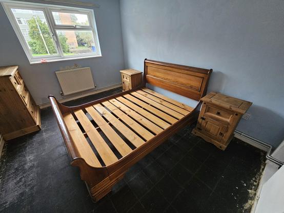 A photo of a large bedroom (for a poor person's version of large) which has a king size bed from the golden age, two pine bedside cabinets, and a chonky dresser.