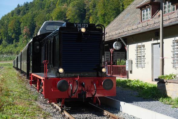 Eine alte schwarze kantige Diesellok mit einer Dachkanzel für Einmannbetrieb mit einem Museums Zug im Bahnhof Behringersmühle