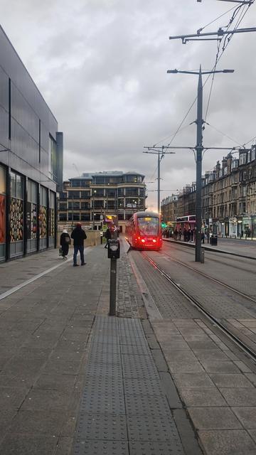 Looking along the tram tracks outside Haymarket railway station, as a tram pulls in at dusk