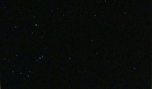Fotografia do céu noturno com várias estrelas, com a constelação de Órion no canto inferior esquerdo em destaque.