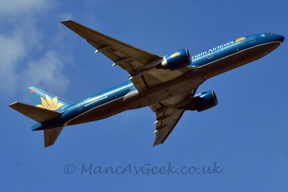 There are white "Vietnam Airlines" titles on the upper forward fuselage, the first few letters obscured by the right engine.
A golden flower is on the forward fuselage, as well as on the blue engine pods under the wings, and in a larger form on the tail.
The registration "VN-A142" is on the upper rear fuselage in white, and under the outer panels of the underside of the left wing, in black.
Blue sky with fluffs of white cloud on the left of the frame fill the rest of the frame.