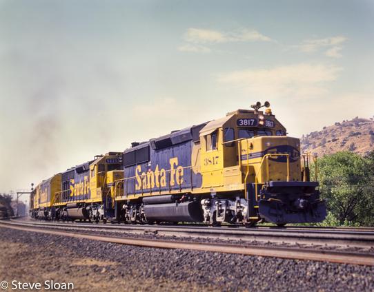 On Friday, June 18, 1982. Atchison, Topeka and Santa Fe Railway (ATSF) 3817 and 5635 led an eastbound at Woodford, CA.