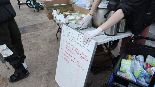 A view from the front of the serving table at RTS. A big pot of pasta is visible on the table, along with a box of PB&J sandwiches and some pots of coffee.