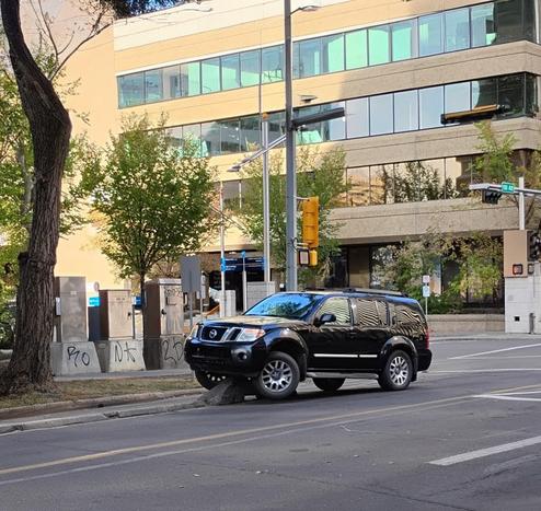 SUV has left the main traffic area on the roadway and has run up on top of a cement thingy that protects bikes in the separated bike lane. The car is stuck, and bikes are safe as long as it is!