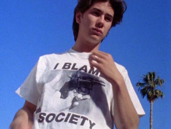 James Duval sur un ciel bleu, portant un t-shirt "I Blame Society"