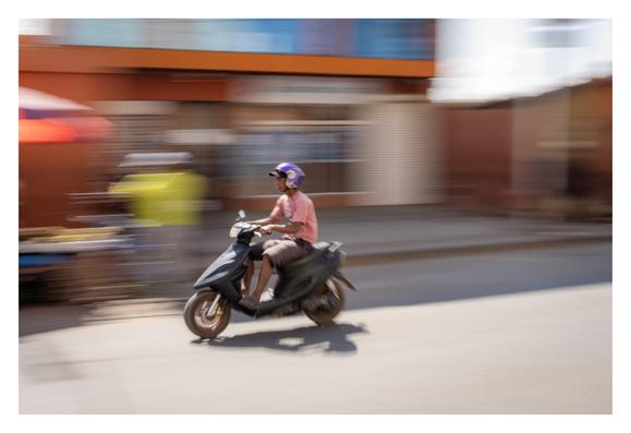 Un scooter qui fonce, dans une rue déserte d'Ivato, un dimanche midi