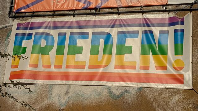 an der Außenfassade des Zentralwerk eine große Plane mit dem Wort "Frieden" horizontal in regenbogenfarben