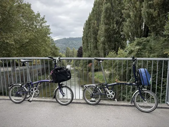 Our two Brompton folding bikes leaning against the railing of a small pedestrian bridge over the Suez in Bienne.