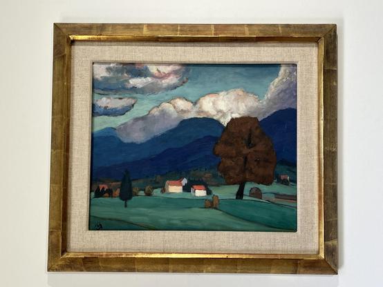 Gabriele, Münter, Landschaft bei Murnau (1935). Hinter dunklen Bergen erheben sich leuchtende Wolken. Im Vordergrund der einzelnen Bäume und Häuser.