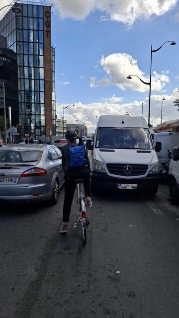 Cycliste cherchant son chemin au milieu des voitures porte de Montreuil