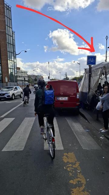 Cycliste cherchant à éviter une camionnette qui bloque l'accès à une piste cyclable