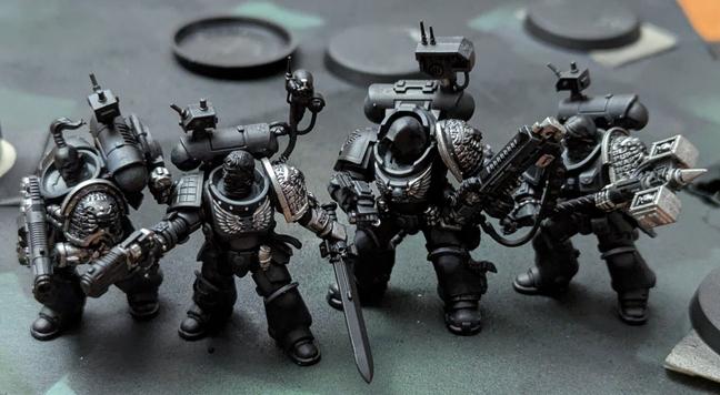 Four Primaris Deathwatch Space Marines. Painted black with some silver details.