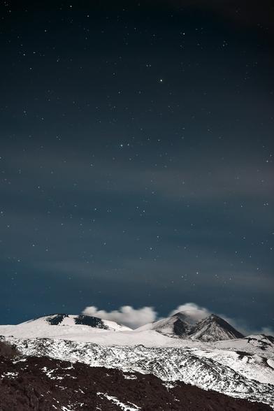the night sky over a snowy mountain range