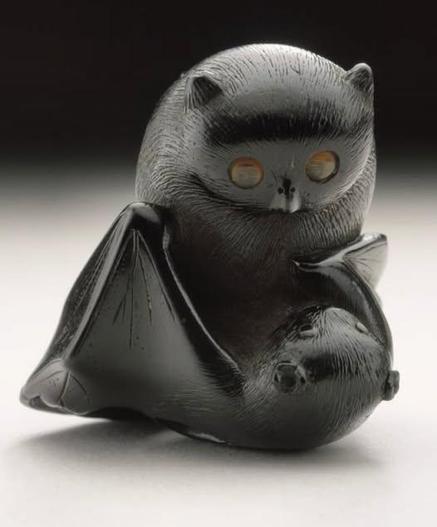 A 19th-century Japanese netsuke, carved from ebony with intricate inlays, showing an owl battling a bat
