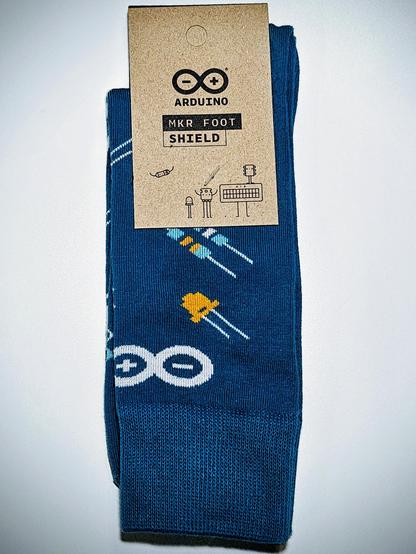blue Arduino socks featuring illustrations of passive components like LEDs and resistors as well as the Arduino logo