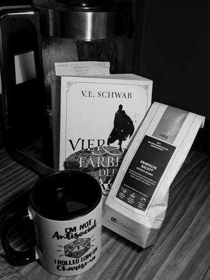 A bag of loose leaf tea (Tea Geschwendner Nr. 901 aka. "Arabische Nacht"), a filled mug with "I'm not antisocial, I rolled low on charisma" written on it and the book leaning against my kettle.
