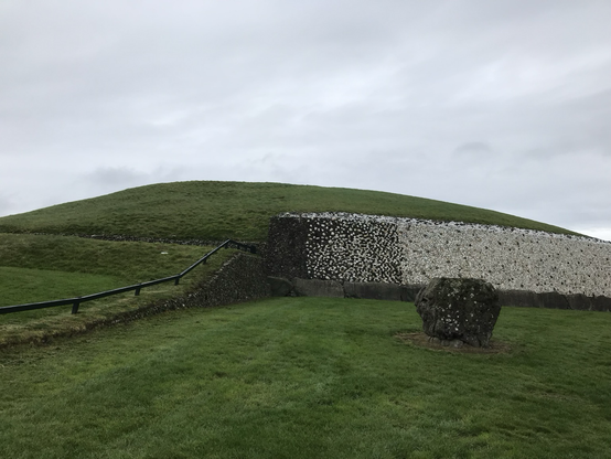 Newgrange and one of its stones on a dull day.