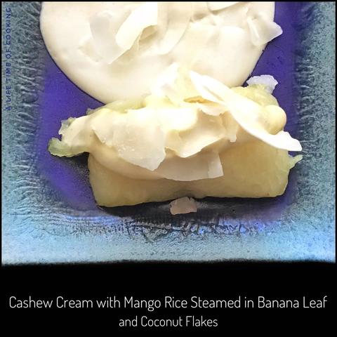 A blue plate containing a roll of mango rice that was steamed in banana leaves, topped with coconut flakes and accompanied by a thick cream made from cashews.