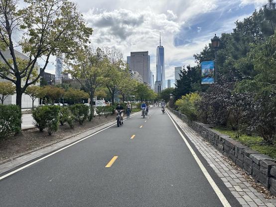 Photo looking down the West Side Bike Path with 1 WTC about a half mile ahead. The sky is bright but cloudy.