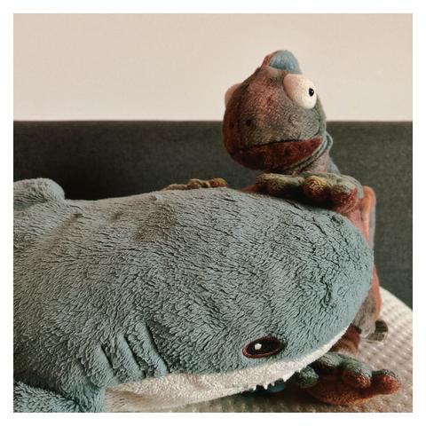 English: A plush chameleon sits behind a plush blåhaj. It looks like the chameleon is petting the shark‘s head.

Deutsch: Ein Plüsch-Chamäleon sitzt hinter einem Plüsch-Blåhaj. Es sieht so aus, als würde das Chamäleon den Kopf des Hais streicheln.