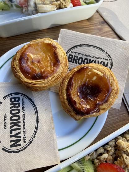2 custard tarts on a plate. Napkins with Brooklyn printed on them are under the tarts