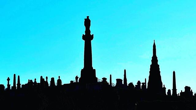 Gravestones silhouetted against a pure blue sky.