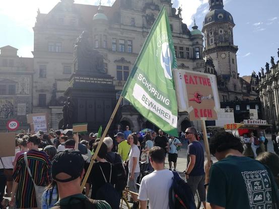 Eine Menschenansammlung. Im Vordergrund die Flagge von Christians for Future.