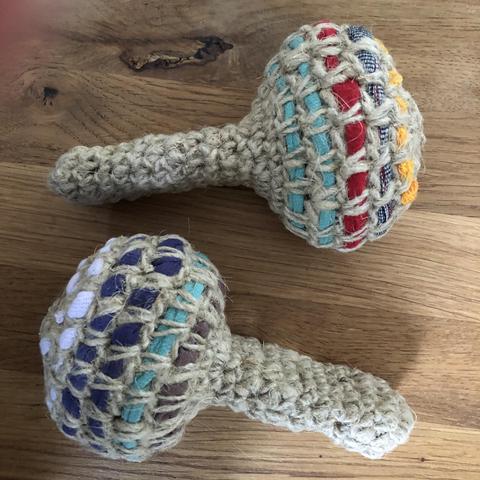 Ich habe im Atelier Mitzi zwei Rasseln hergestellt, indem ich zwei Messlöffel mit Maiskörnern befüllt, zusammengefügt und mit Jutegarn und Alttextilien umhäkelt habe.