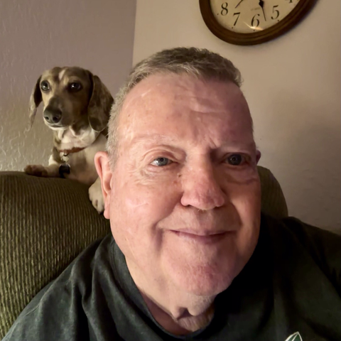 Dachshund perched behind man in easy chair