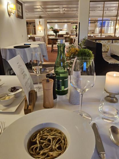 Blick in den Speiseraum eines Hotels. Auf dem Tisch am unteren Bildrand ist ein Teller mit Frittatensuppe zu sehen.